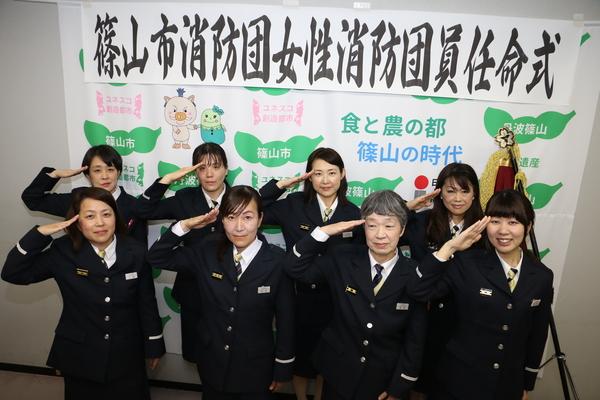 制服を着た8名の女性消防士が、敬礼のポーズを取っている写真