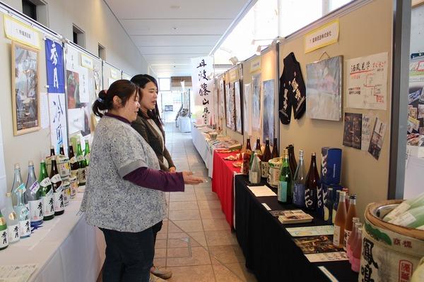 女性2人が、展示されているお酒を指さして話をしている写真