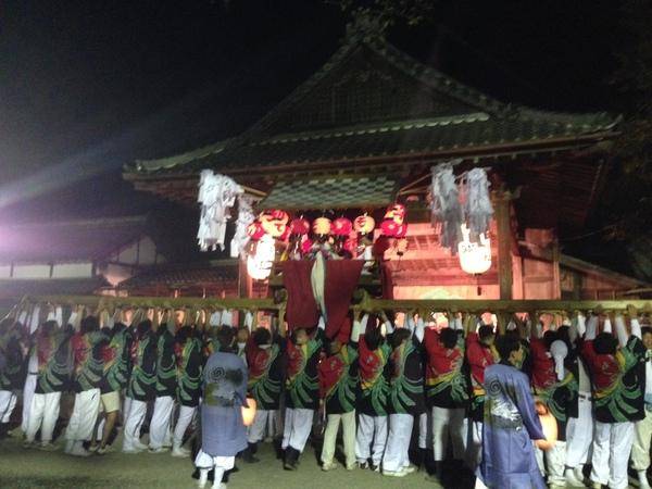 法被姿の人々が提灯に灯りのともった神輿を持ちあげている写真