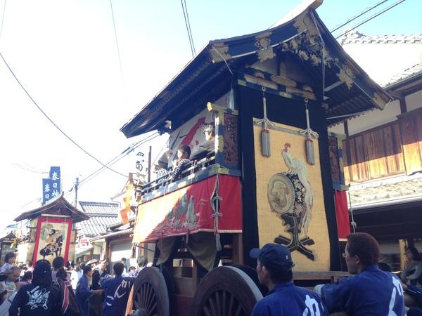 横笛を吹いている子供らが乗っている鉢山を押しながら城下町を練り歩いている写真