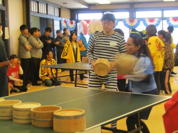 警察官姿の女性と囚人服を着た男性が桶で卓球をしている写真