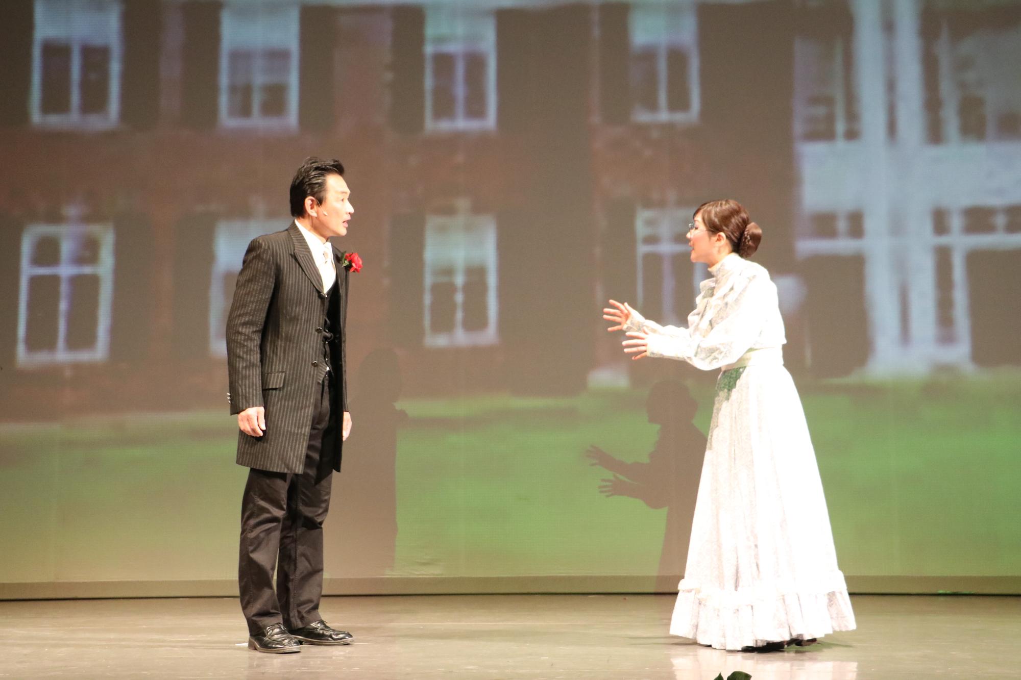 白い服を着た若き日のサリバン先生と背広姿の男性が向かい合って話をしている写真