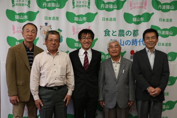 5名の男性が写っており、中央に岩崎 智彦さんが笑顔で写っている写真