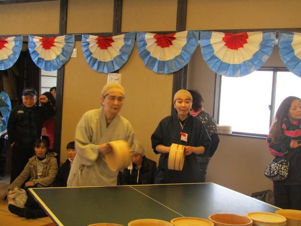 甚兵衛を着て、顔にひげをかいた男性と女性が桶で卓球をしている写真