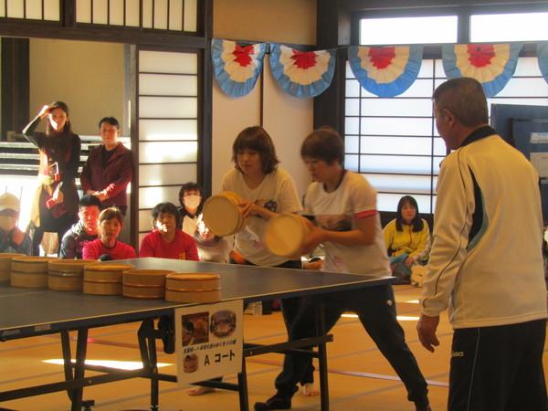 Tシャツとジャージを着た女性2人が桶で卓球をしている写真