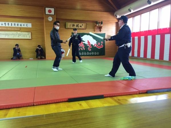 右手に刃物を持った犯人に扮した警察官に、白い棒を右手に持って向かっていく2名の警察官が披露する逮捕術の写真