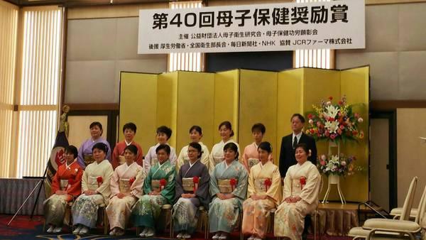 金屏風の前で14名の着物を来た女性たちと、スーツを来た男性1名が並んでいる写真