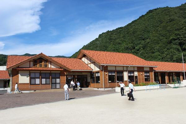 青空の下、組合立篠山小中学校の周りにいる7名の男性の写真