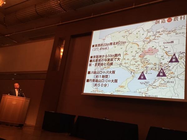 篠山市長が、スライドに映っている篠山周辺の地図を見ながら話をしている写真