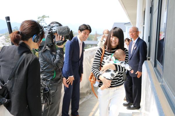 子供を抱っこしているお母さんを放送局の方が微笑ましく見ている写真