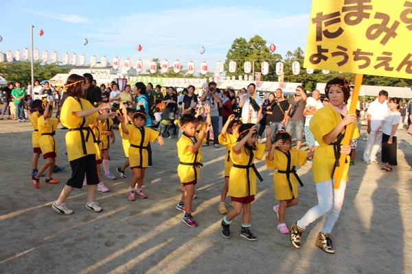 黄色の法被にねじり鉢巻きの幼稚園の園児と先生が踊っている写真