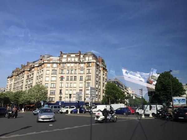ビルの前に車と車が交差するパリ市街の写真