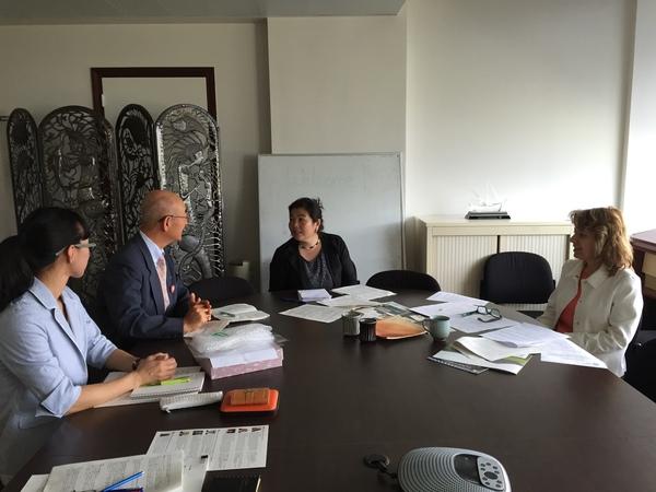 丸テーブルに資料が置かれ、デニスルックスさんや関係者の方とお話をしている市長の写真