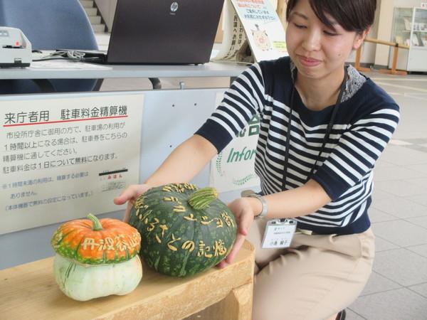 日本遺産の文字が入った南瓜2個を職員の女性が並べている写真