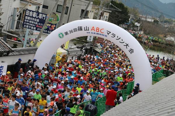 大きな風船で「篠山ABCマラソン大会」と書かれた下を沢山の選手が走っている写真