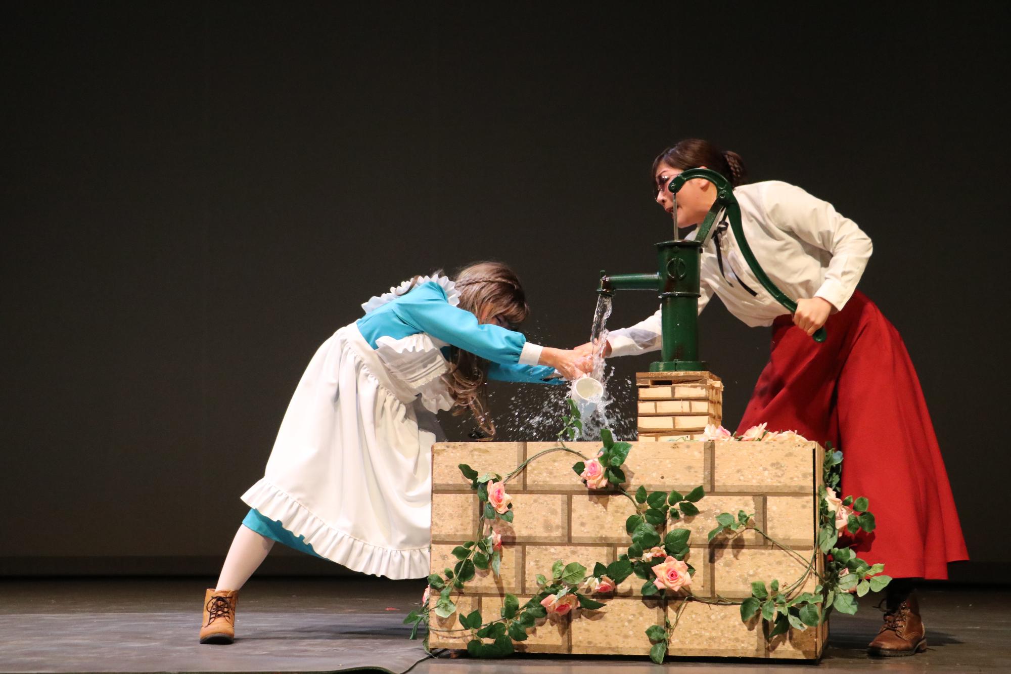 井戸のようなところで、サリバン先生が水を引き、ヘレンにコップを持たせて水に触れさせている写真