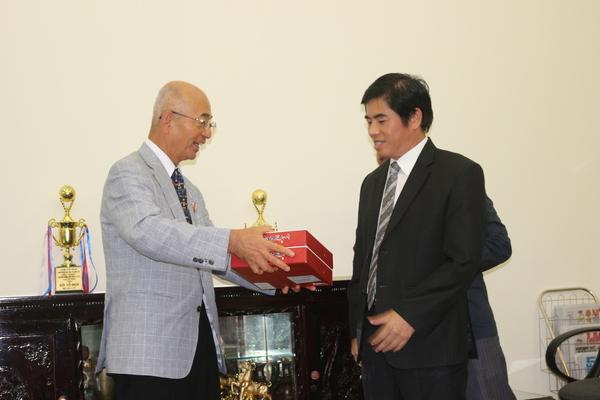 スーツを着た医療大学の校長の男性に市長が赤い箱を渡している写真