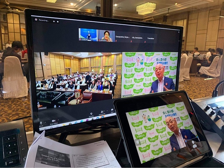 市長がフォーラムで発言している様子と、現地会場の様子がパソコンに映し出されている