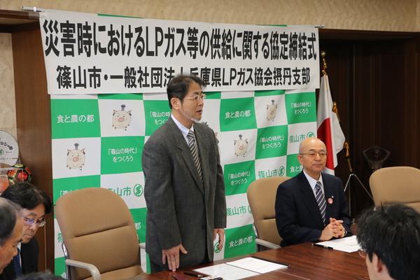 椅子に座っている市長の横で支部長の市野さんが立ってお話しをしている写真