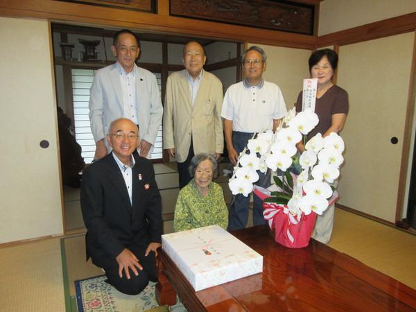 長寿祝福者 本田はな子さん(102歳)が市長らとお祝いの胡蝶蘭と記念品を前に記念撮影している写真