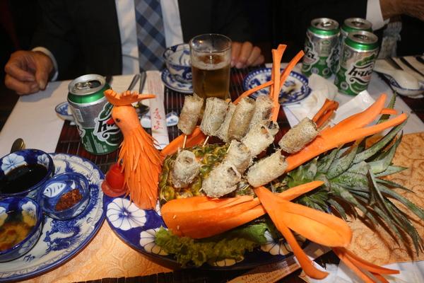 人参とパイナップルとロール状の食べ物で装飾された鶏の形の食べ物の写真
