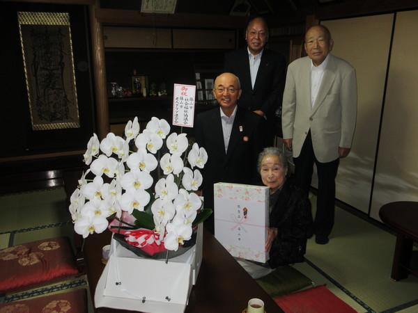 長寿祝福者 小林ふみ子さん(101歳)が市長らとお祝いの胡蝶蘭と記念品を前に記念撮影している写真