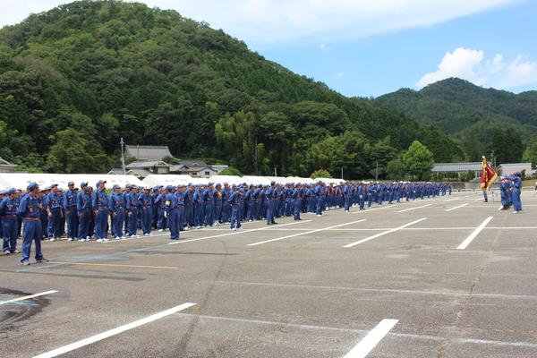 青空の下に整列する青いユニフォームを着た消防団員たちの写真