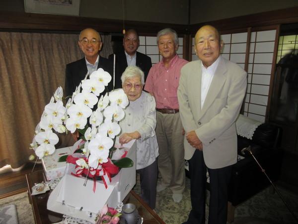 長寿祝福者 菅野きよ子さん(101歳)が市長らとお祝いの胡蝶蘭と記念品を前に記念撮影している写真