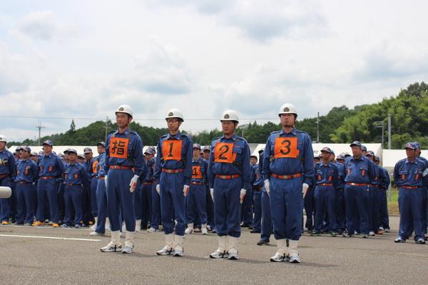 小型ポンプの部優勝の岡野地区の4名の団員が、たくさんの団員の前で整列している写真