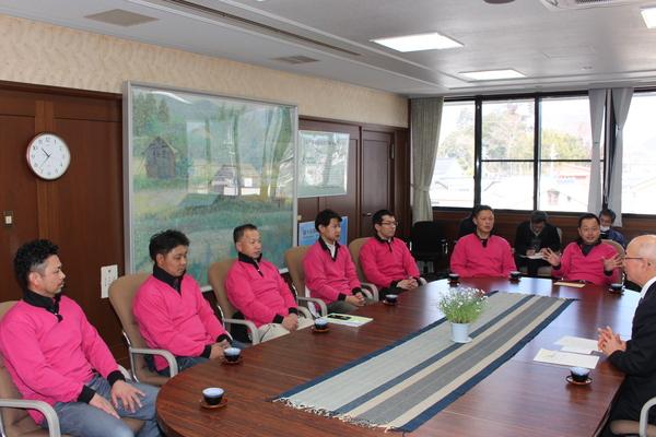 7名の選手が市長を訪問し、円卓に座り談話している写真