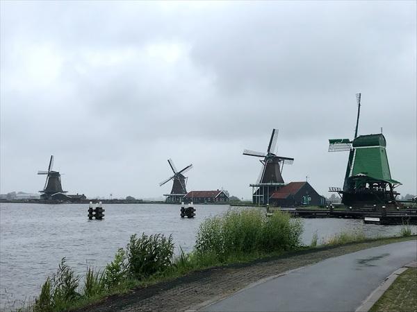 大きな湖の奥に4基の風車が建っている写真
