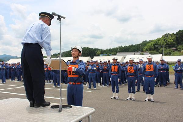 1名の男性が拍手をする団員の前で、賞状を受け取っている写真