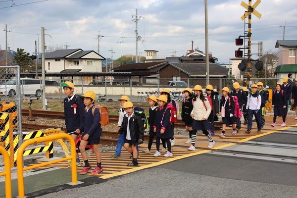 弁天踏切の歩道を歩く小学生らの写真