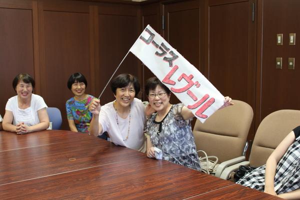 コーラス・レヴールと書かれた旗を持って笑顔で写っている女性の写真