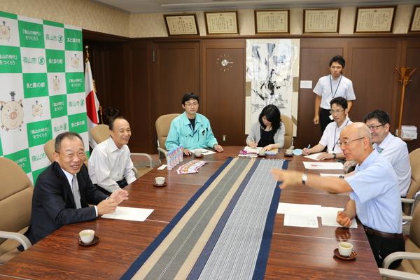 丸いテーブルの周りに5名の男性と1名の女性と市長が座って話をしている写真