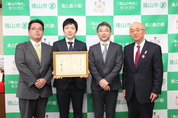 賞状の入った額を持った住倶楽部3名が市長と一緒に記念撮影している写真