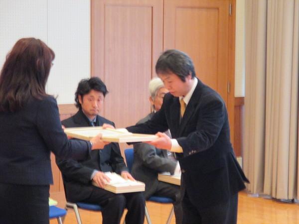 男性が賞状を受け取りながら頭を下げている写真