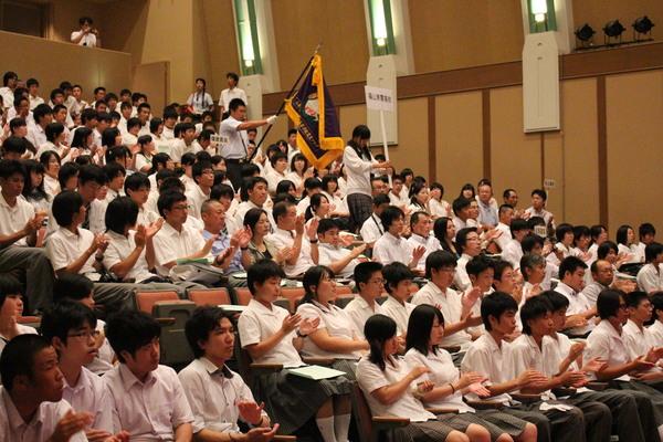 各高校の参加者、学校ごとに観客席に座り拍手をしている様子の写真