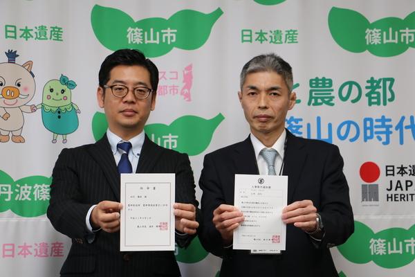 山本 高久さん、田代 優秋（たしろ ゆうしゅう）さんが人事辞令書を持って写っている写真