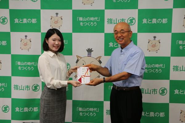 市長と小林さんが奨励金を持って笑顔で写っている写真