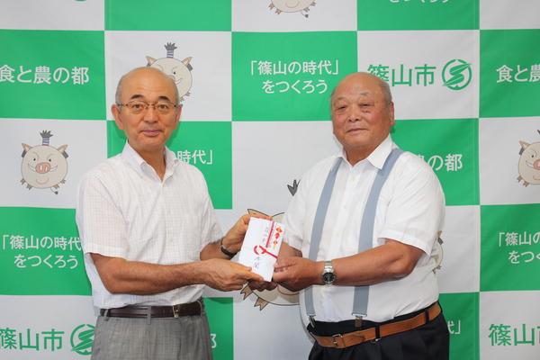 井関 道夫さんと市長が一緒に祝儀袋を持っている写真