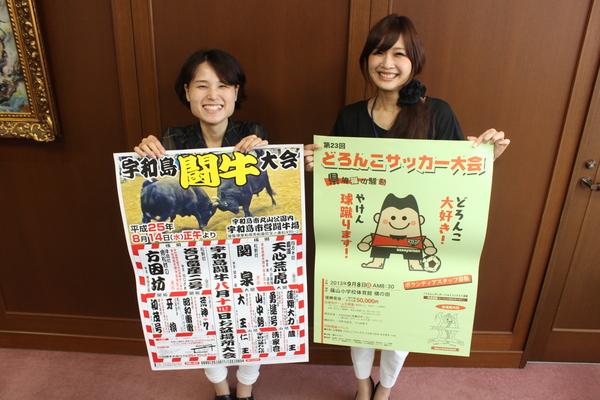 笑顔で、闘牛大会と、どろんこサッカーのポスターを持つ女性2名の写真