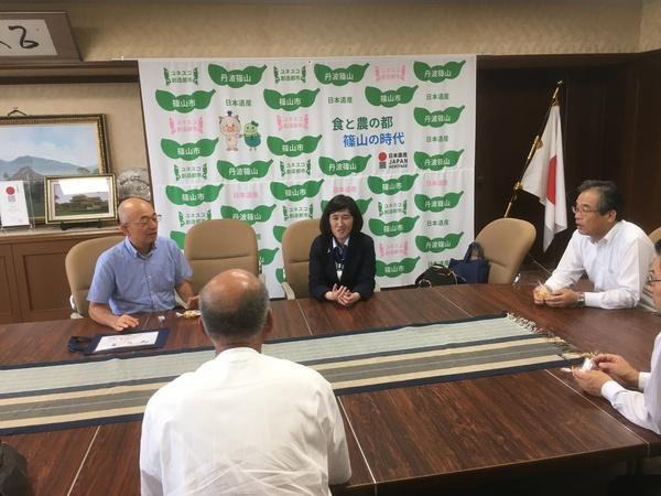 成瀬 淳子さまとスーツを着た男性数名がテーブルで話をしている写真