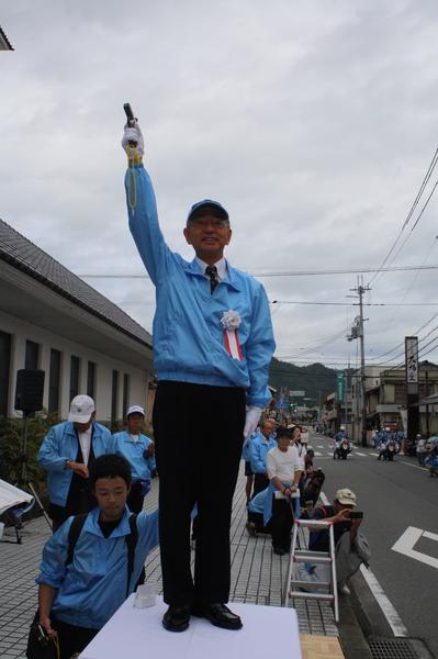 市長が右手を上げ、スタートの合図にピストルを鳴らそうとしている写真