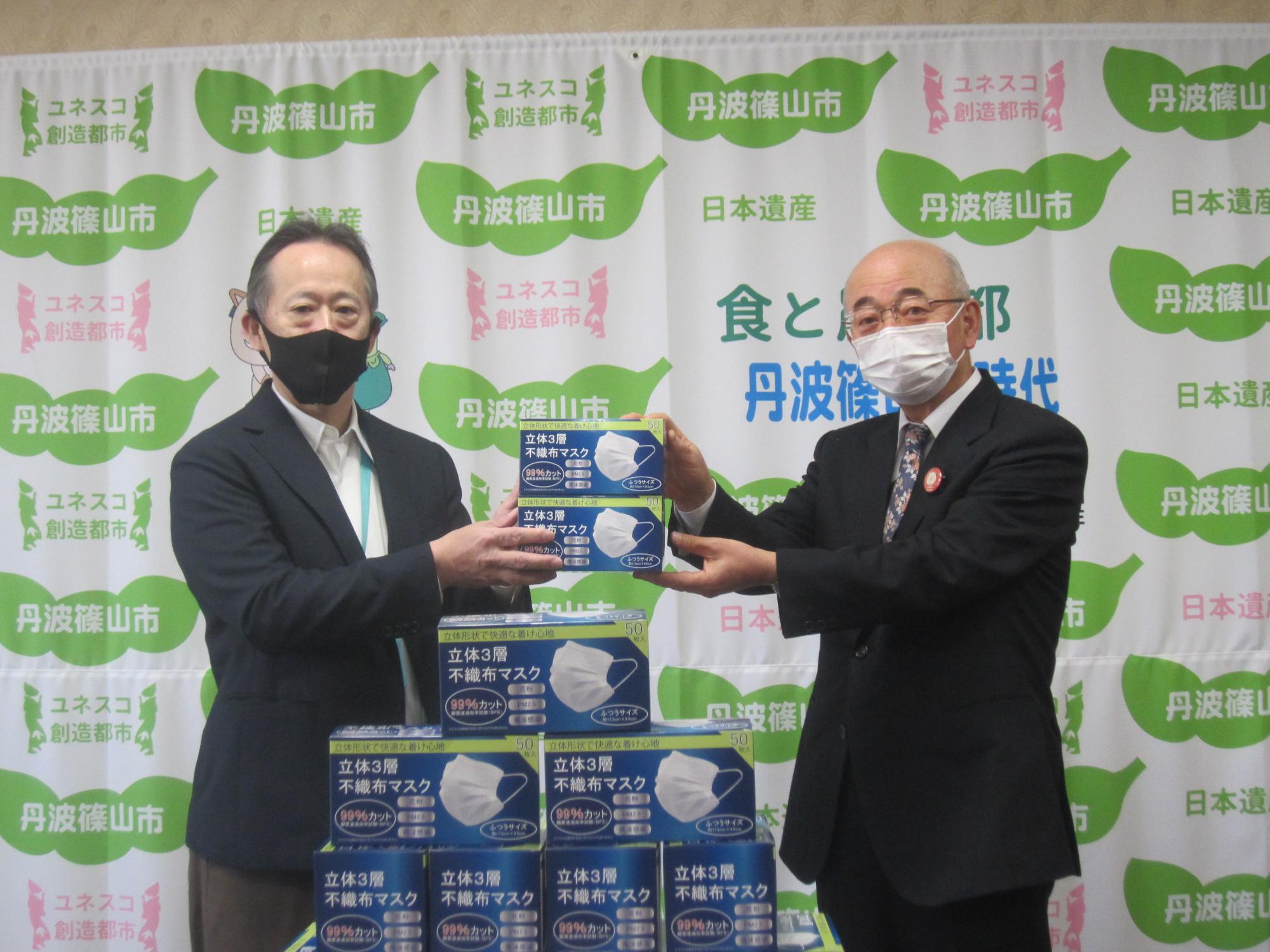 マスクを手にとり記念撮影する市長と支社長