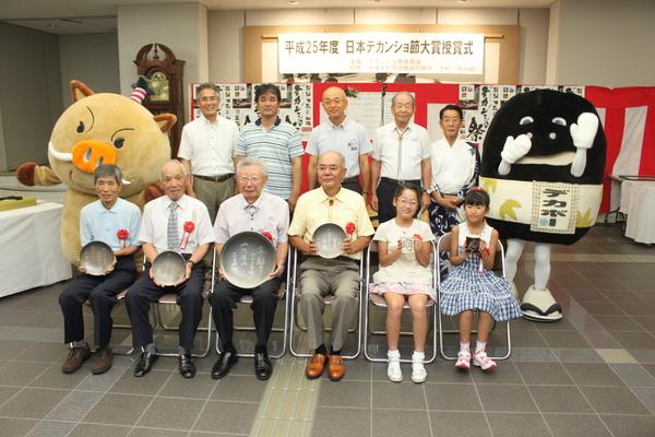 受賞者と関係者、ゆるキャラのまるいのとデカボーの集合写真