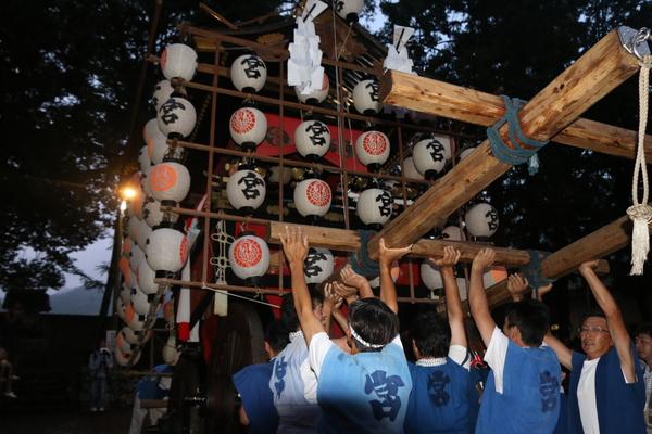 法被姿の男性らが提灯の下げられた山車を持ちあげている写真