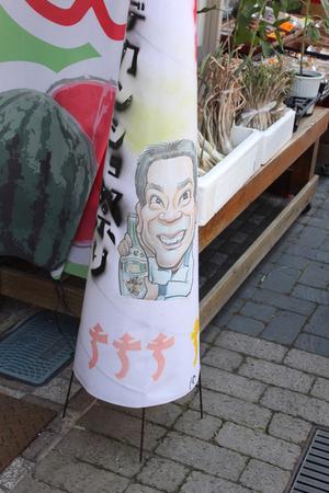 すいかの描かれた上り旗の前に酒を持った男性が描かれているあんどんが置いてある写真