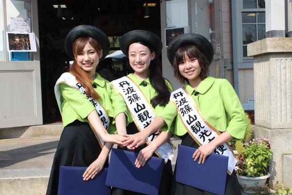 第4代丹波篠山観光大使任の中村 優衣さん、野原 美春さん、原 亜理沙さんが左手に書類を持ち、3人の右手を合わせ笑顔で記念写真