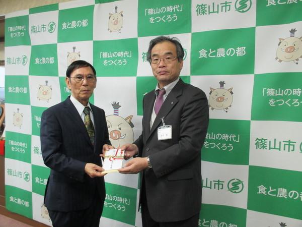 東田 英捷様と副市長の2人が両手で寄付金を持っている写真
